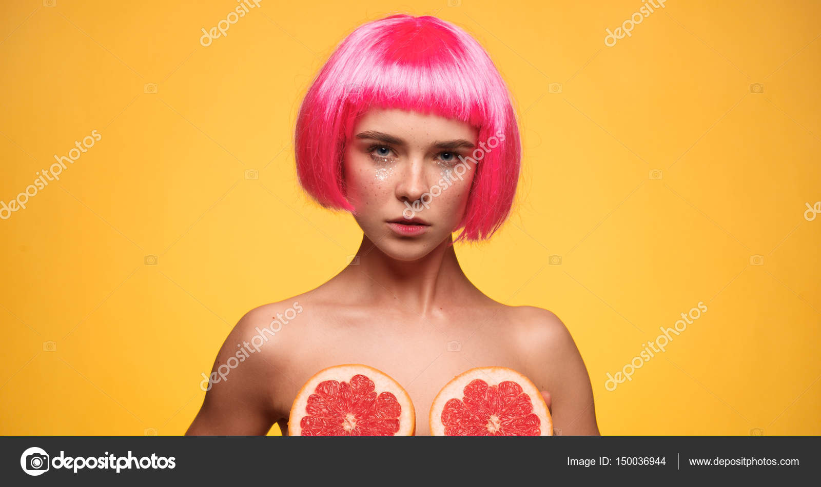 Красивая женщина с розовыми волосами смотрит в камеру и покрывает грудь пол...