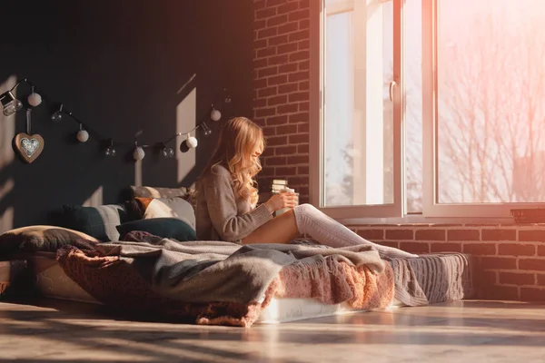 Жінка сидить на ліжку на сонячному світлі — стокове фото