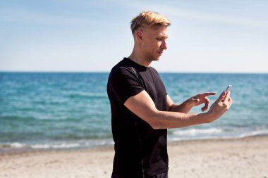 Kumlu sahilde duran genç adam