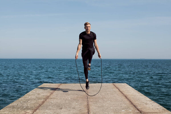 Fit man jumping rope on pier