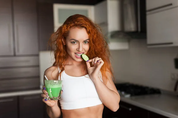 Mulher com smoothie mordendo um pepino — Fotografia de Stock