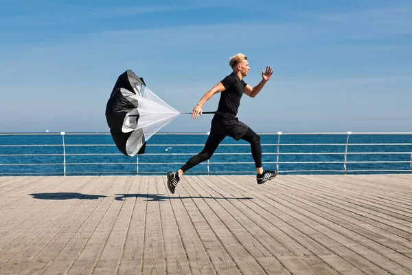 Man met parachute uitgevoerd op pier — Stockfoto