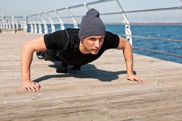 Homem fazendo flexões em frente ao mar — Fotografia de Stock