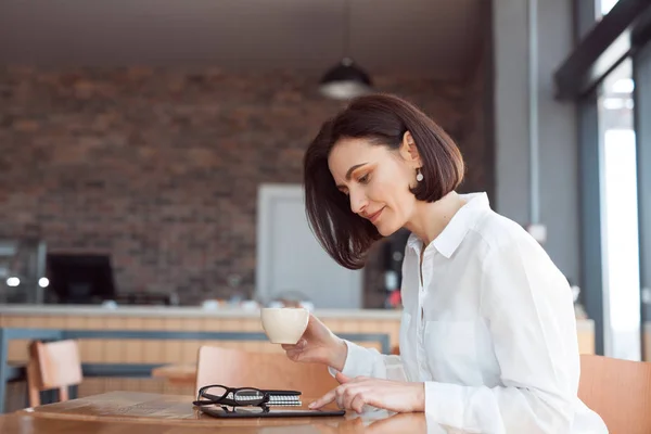 Woman using laptop and drinking coffee — Stock Photo, Image