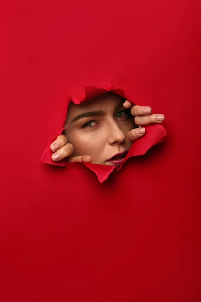 Woman tearing red cardboard with hands — Stock Photo, Image