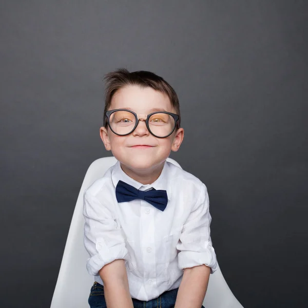 Чарівний хлопчик в окулярах посміхається на камеру — стокове фото
