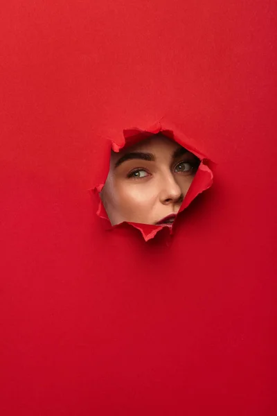 Woman looking through hole in paper — Stock Photo, Image