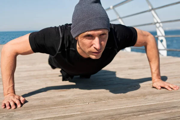 Sportsman gör armhävningar på piren — Stockfoto