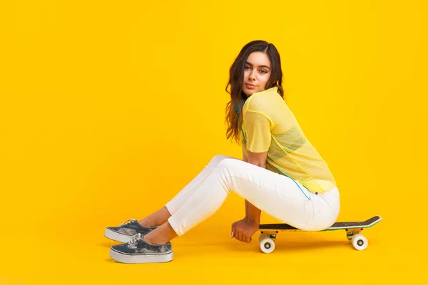 Mladá žena sedí na skateboardu — Stock fotografie