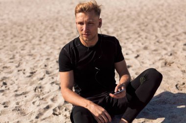 kum ile smartphone üzerinde oturan adam