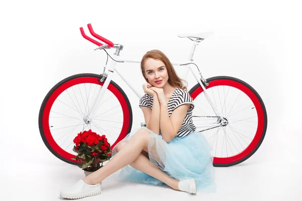 Молодая девушка сидит рядом с велосипедом — стоковое фото