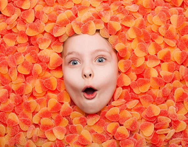 Kid lying in fruit jellies — Stock Photo, Image