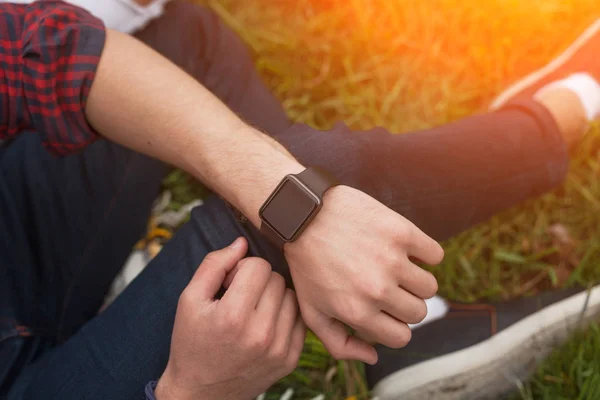 Homem sentado na grama com smartwatch — Fotografia de Stock