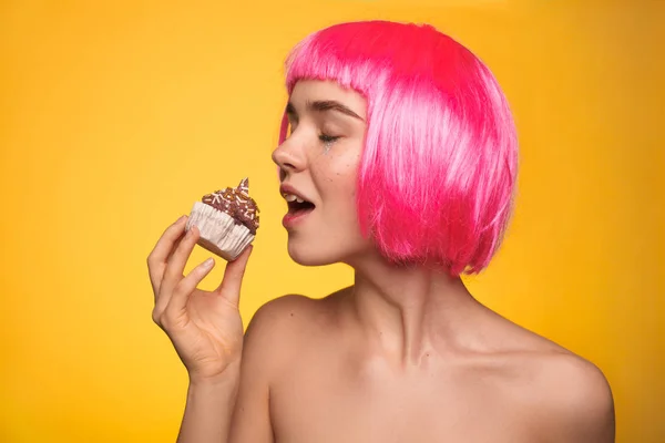 Woman in wig biting cupcake — Stock Photo, Image