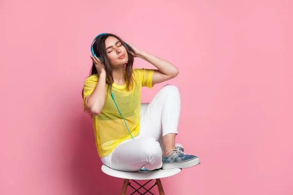 Mujer joven escuchando música en silla — Foto de Stock