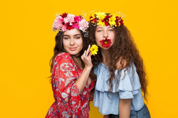 Dos chicas atractivas posando con flores — Foto de Stock