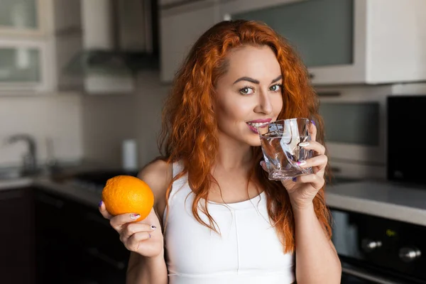 Mulher com laranja e copo de água — Fotografia de Stock