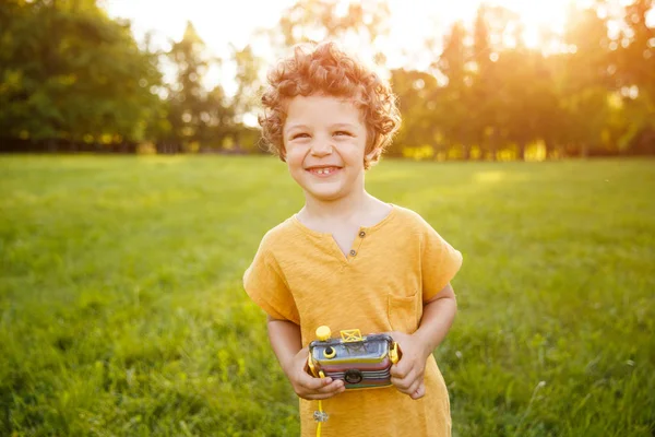 Усміхнена дитина в помаранчевій сорочці тримає камеру — стокове фото