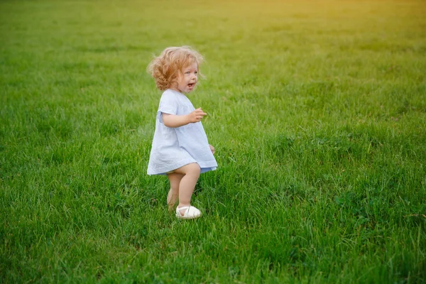 Menina em vestido azul andando na grama — Fotografia de Stock