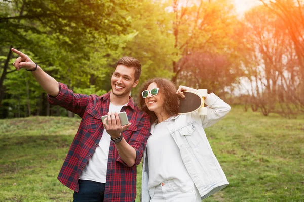 Kerl mit Smartphone und Mädchen mit Kreuzer — Stockfoto