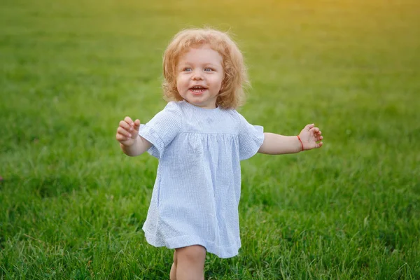 Молода дівчина ходить по траві посміхаючись — стокове фото