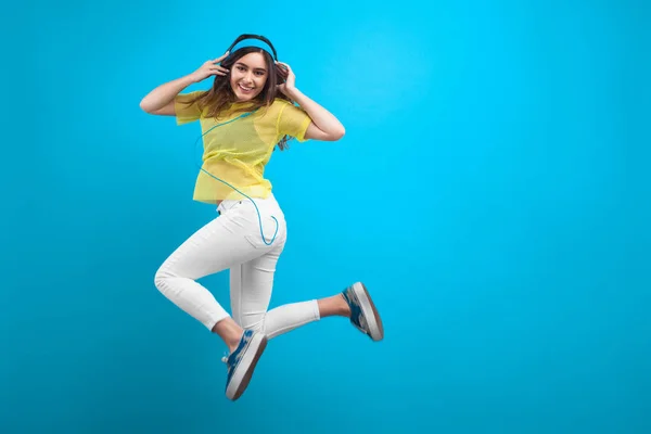 Sorrindo morena menina em fones de ouvido pulando — Fotografia de Stock