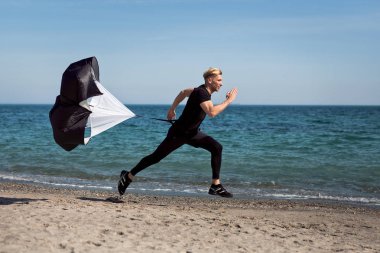 Paraşüt ile kumsalda koşan adam