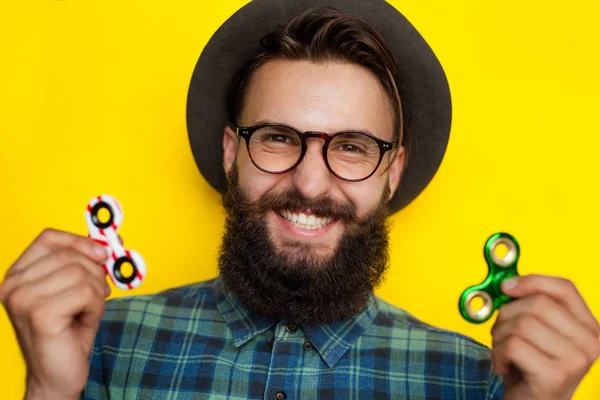 Sorrindo barbudo jovem com dois spinners — Fotografia de Stock