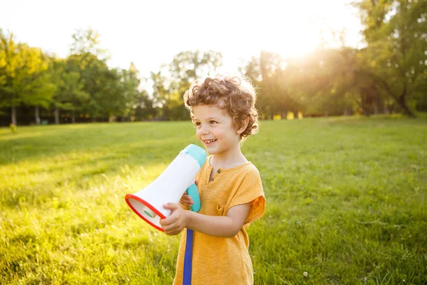 Jonge jongen permanent in park holding luidspreker — Stockfoto