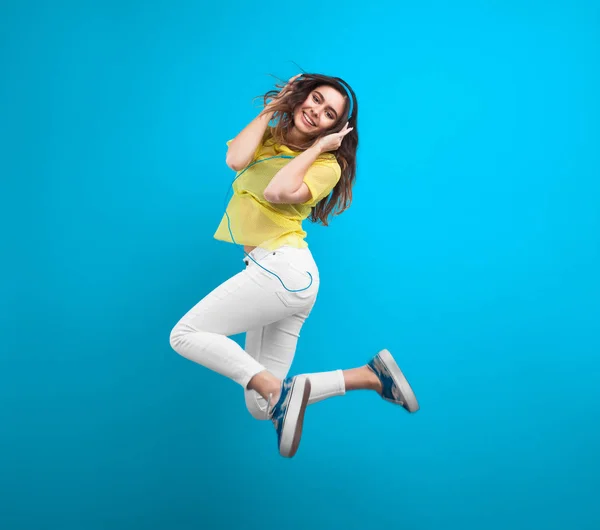 Tonårig flicka hoppande innehav hörlurar — Stockfoto