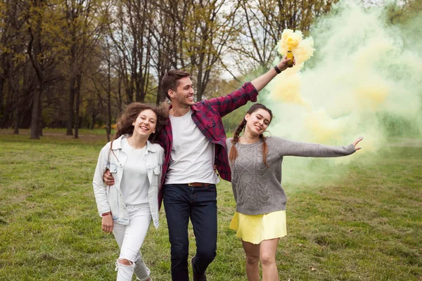 Jovens caminhando com fumaça colorida no parque — Fotografia de Stock