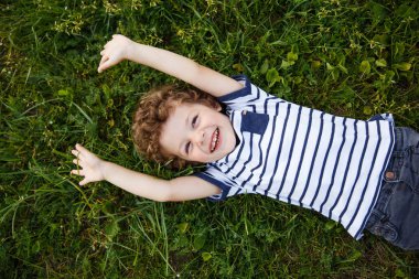 Neşeli çocuk çimenlerin üzerinde poz
