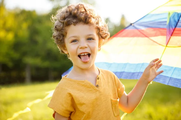 Ung pojke lägger ut tungan innehav kite — Stockfoto