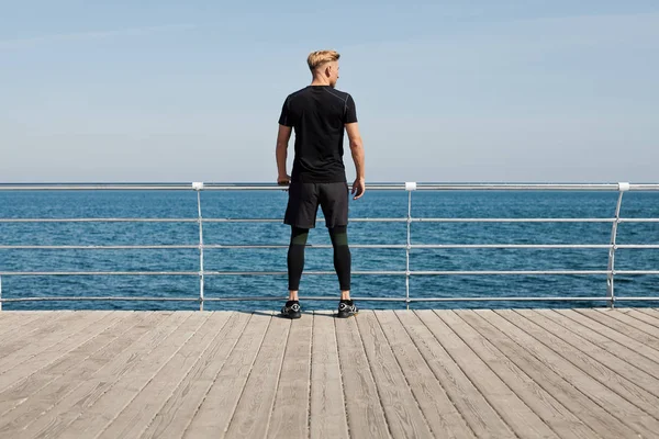 İskele üzerinde sportif kıyafet duran adam