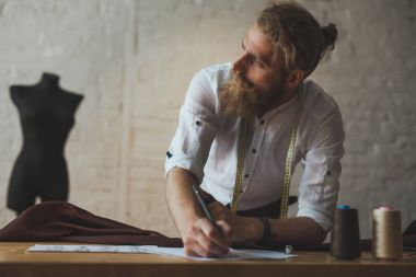 Masanın üzerine eğilerek düşünceli sakallı adam
