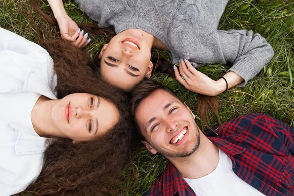 Due ragazze e ragazzo sdraiato sull'erba — Foto Stock