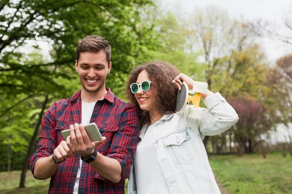 Vrienden kijken naar smartphone op park — Stockfoto