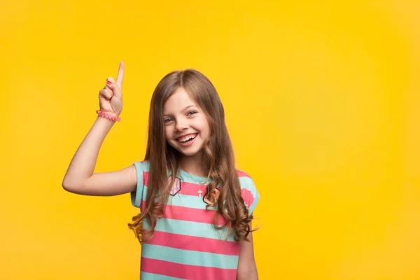 Весела маленька дівчинка вказує на помаранчевий — стокове фото