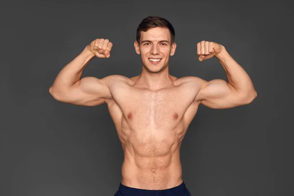 Jovem desportista mostrando músculos — Fotografia de Stock