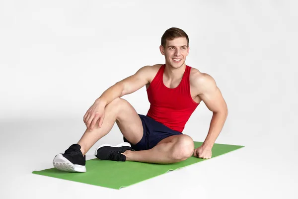 Fit man sittande på matta — Stockfoto