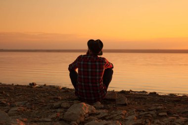 Nehir kıyısında oturan adam