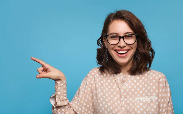 Chica alegre en gafas apuntando hacia fuera — Foto de Stock