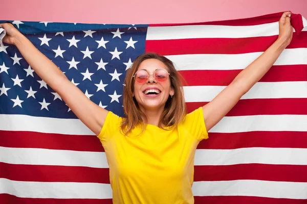 Laughing woman with flag on pink