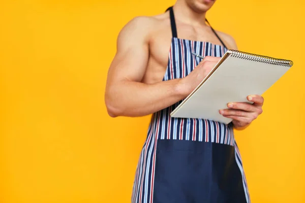 Crop man in apron writing in notepad — Stock Photo, Image