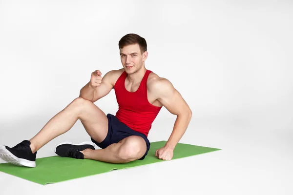 Muskulöser Mann sitzt auf Matte — Stockfoto