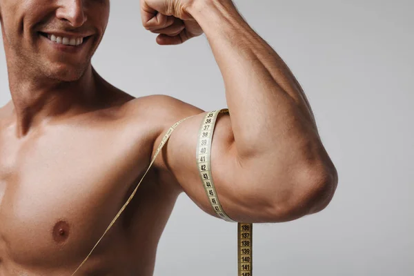 Crop smiling man measuring biceps — Stock Photo, Image