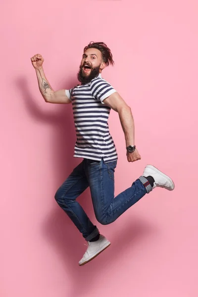 Возбужденный человек позирует в прыжке на розовый — стоковое фото