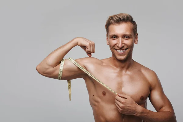 Glimlachend sportieve man meten biceps — Stockfoto
