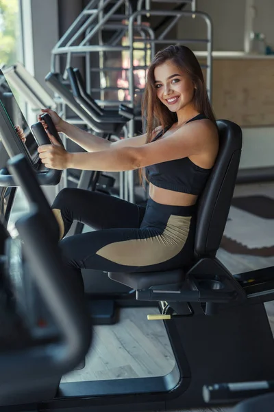 Femme souriante sur la machine de gymnase — Photo