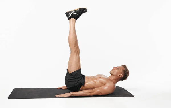 Hombre en forma haciendo ejercicio con las piernas hacia arriba — Foto de Stock